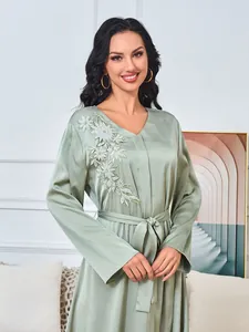 Gedetailleerde weergave van een elegante saliegroene maxi-jurk met bloemig borduurwerk en kralen.