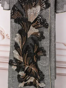 Détail de broderie florale de luxe en sequins noirs et argentés sur une robe grise