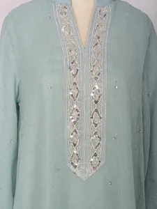 Gros plan sur une robe caftan bleu clair avec broderies de paillettes et de perles.