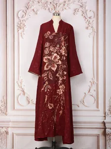 Vue détaillée d'une robe longue bordeaux avec des broderies florales complexes en paillettes dorées