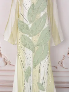 Dettaglio di abito elegante con applicazioni a foglia e ricami di paillettes argento.