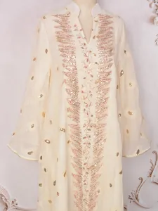 Dettaglio di un abito in rete avorio con ricami in paillettes dorate e scollo a V elegante