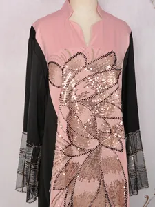 Détail d'une robe rose ethnique avec des fleurs en paillettes dorées et manches perles