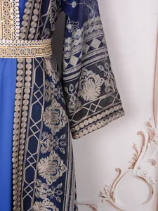 Detailed view of the intricate gold and silver floral embroidery on a blue kaftan dress