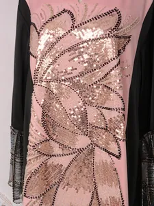 Gros plan détaillé de la broderie complexe de paillettes dorées sur une robe rose
