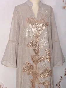 Gros plan d'une robe champagne élégante avec des broderies de paillettes dorées fines