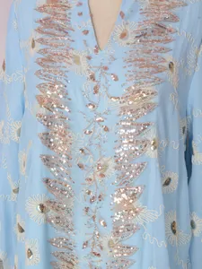 Primo piano di perline dorate e paillettes su un abito in tulle celeste ricamato