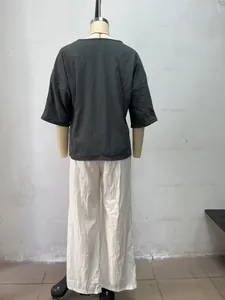 Rückansicht eines eleganten böhmischen Sets aus lockeren grauen Oberteil und weißer Hose