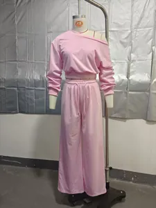 Detail view of pink two-piece tracksuit with off-shoulder top and wide-leg pants.