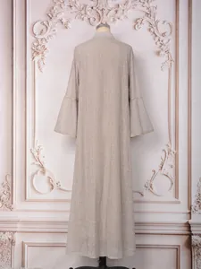 Détail de la broderie de paillettes et des manches cloche sur une robe caftan beige