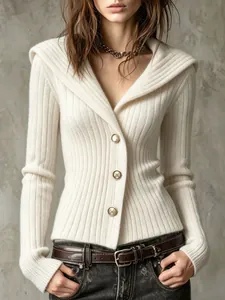 Détail d'un cardigan en maille côtelée blanche à coupe ajustée avec boutons dorés pour femmes.