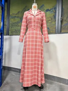 Close-up van het roze ruitpatroon en de knoopdetails op de maxi-jurk met lange mouwen