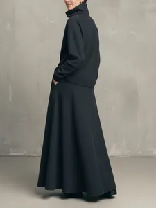 Back profile view of a minimalist charcoal high neck sweater and long A-line skirt set