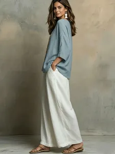 Ganzkörperaufnahme eines eleganten Bohemian-Sets mit blauem Oberteil und weißer Weithose.