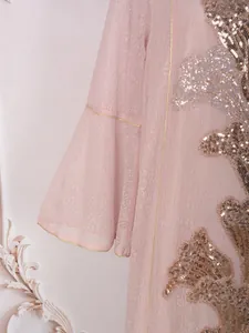 Gros plan d'une élégante robe rose ornée de broderies complexes en paillettes dorées.