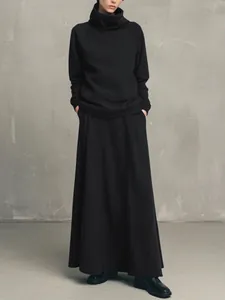 A minimalist black high-neck sweatshirt paired with a matching maxi skirt on a model