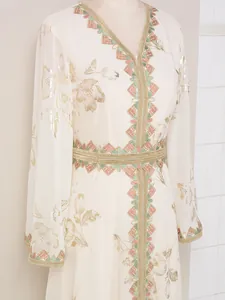Detalle de un elegante caftán crema con estampado floral de pan de oro y bordados