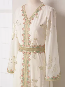 Primer plano detallado de un elegante vestido largo crema con motivos florales dorados
