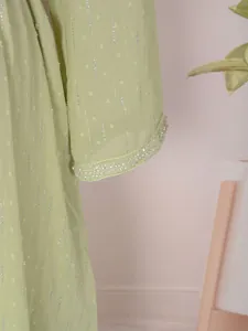 Détail de la manche d'une robe longue vert clair avec rayures argentées et perles délicates