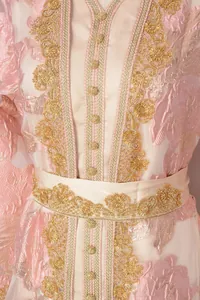 Close-up detail of an elegant pink kaftan dress with intricate gold embroidery and beading
