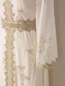 Detalle de un vestido largo étnico con bronceado floral dorado y bordado colorido.