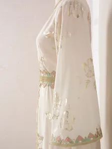 Primer plano del elegante estampado floral dorado y ribete bordado en vestido caftán crema