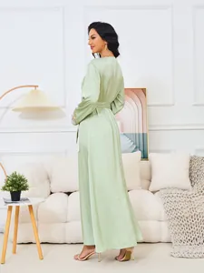 Vista trasera del elegante vestido largo verde claro con cuello en V, strass y manga larga.