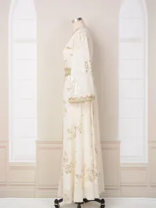 Vista lateral detallada de vestido largo étnico crema con elegante estampado floral oro