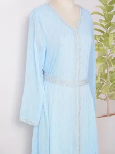 Détail d'une robe longue bleu clair avec rayures scintillantes et bordure argentée.