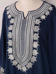 Détail rapproché de la broderie cœur argentée complexe sur ce beau caftan bleu marine