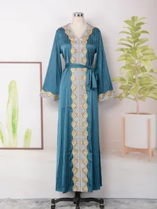Detalle del vestido largo verde azulado con cuello en V, encaje dorado y pedrería