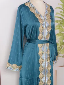 Detalle de vestido largo verde azulado con encaje dorado y brillantes de imitación.
