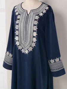 Vue détaillée de la broderie cœur argentée sur l'encolure d'une robe caftan bleu