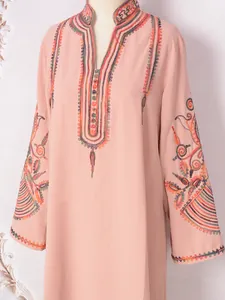 Detalle de vestido rosa de manga larga con bordado étnico colorido en el escote.