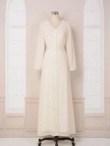 Détail d'une élégante robe longue crème à manches longues avec dorures et perles