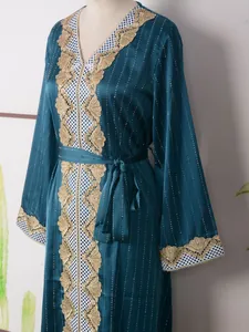 Detalle de un elegante vestido de fiesta verde azulado con encaje dorado y pedrería