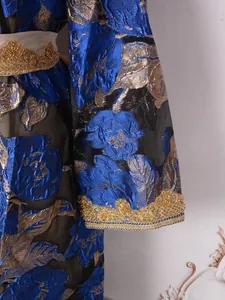 Close-up of heavy gold beading and blue floral brocade fabric on a luxury party dress