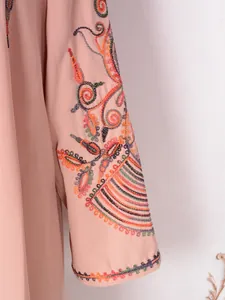 Primer plano de vibrantes bordados florales y abalorios en la manga de un vestido rosa.
