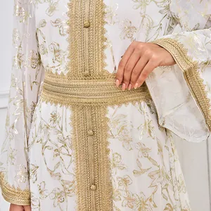 Gros plan d'une robe abaya blanche avec imprimé floral doré et bordure en dentelle