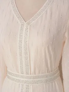 Détail d'une robe rose clair avec décolleté en V à paillettes argentées et rayures