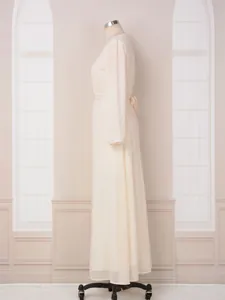 Vue latérale d'une robe longue crème avec une élégante texture dorée et des manches longues