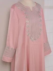 Vue détaillée de la broderie cœur argentée sur le col et les poignets d'un caftan rose