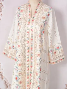 Detail eines weißen Kaftan-Maxikleides mit floraler Paillettenstickerei und V-Ausschnitt