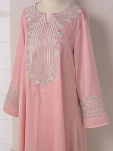 Détail de la robe caftan rose avec une élégante broderie florale argentée sur le col.