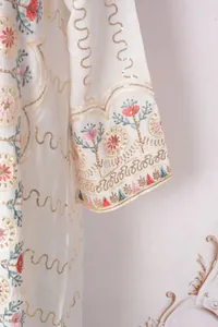 Detailansicht der feinen Blumenstickerei und Goldpailletten auf weißem Kleid MT389