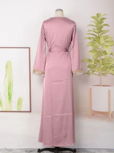 Vista trasera detallada de vestido largo rosa con pedrería y puños de encaje dorado en maniquí