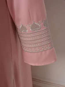 Gros plan sur la broderie argentée en forme de cœur sur la manche d'une robe rose