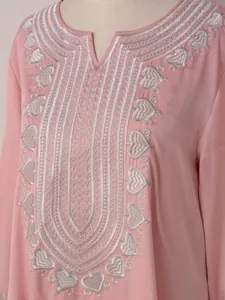 Détail de la broderie cœur argentée sur l'encolure d'une robe tunique rose ethnique.