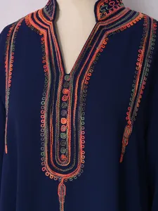 Detalle de bordados étnicos coloridos en un vestido azul marino con escote en V y cuentas