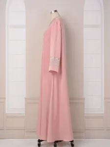 Vue latérale d'une élégante robe rose à manches longues avec broderie détaillée